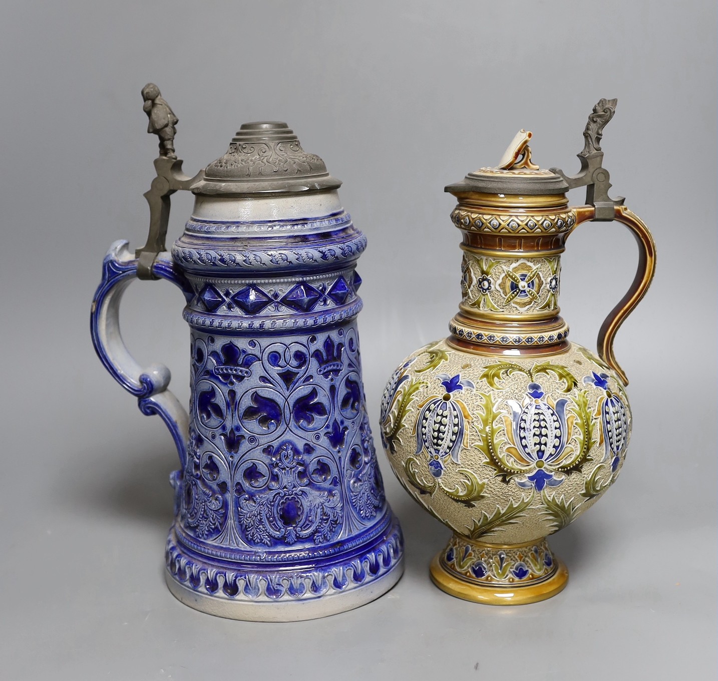 A Mettlach stoneware stein, 29.5 cm high, a German blue stoneware stein, a Staffordshire porcelain cottage pastille burner and an English porcelain floral plate